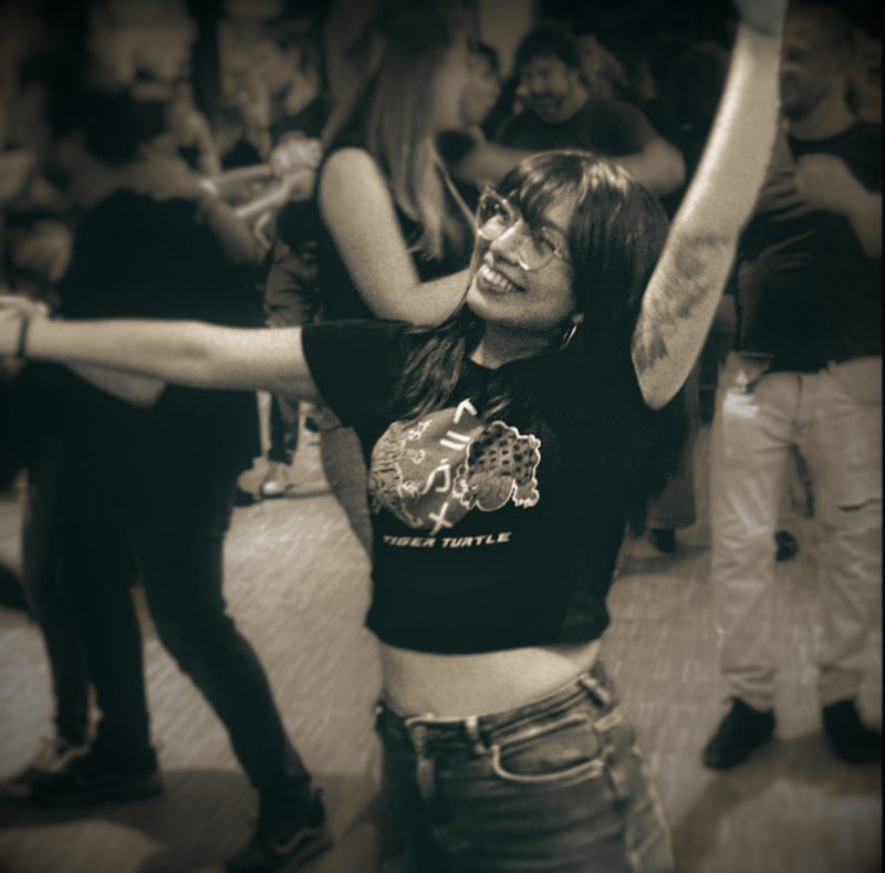 Rosa Oroya bailando con los brazos abiertos en una pista llena de gente